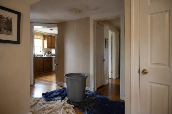 Bucket catching a roof leak inside a Massachusetts home