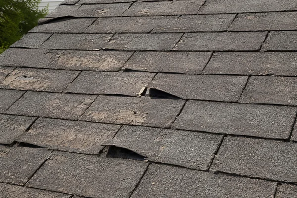 bald spots and curled asphalt shingles signaling roof replacement