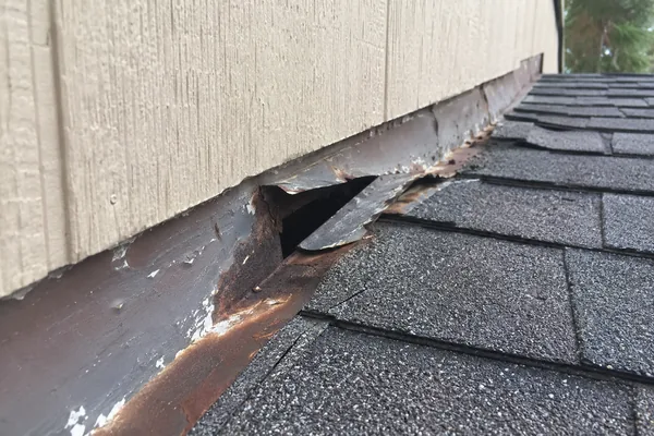 Lifted flashing at a sidewall after wind, photographed during a Worcester storm damage assessment