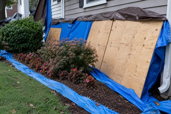 plywood and tarp protecting flower beds during a Massachusetts roof replacement