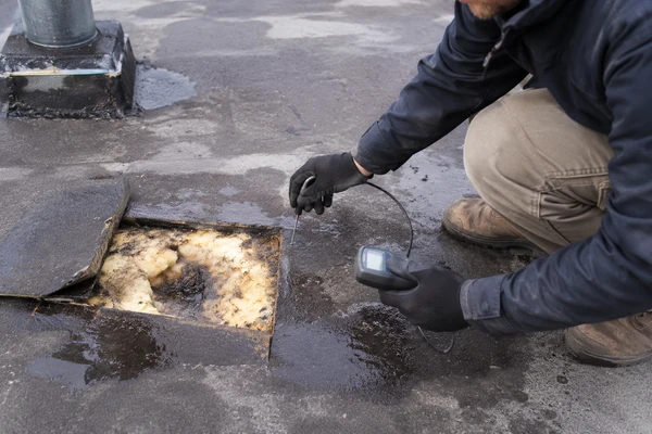 Moisture reading taken on a commercial roof to decide recover against replacement