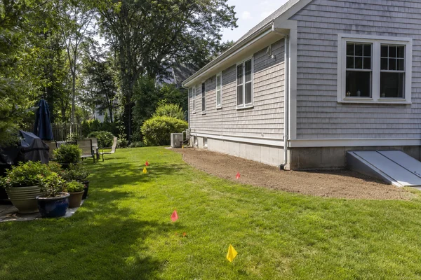 yard prepped for a roof replacement with plants moved and sprinkler heads flagged