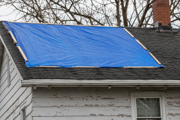 tarp secured over a leaking roof as a temporary fix