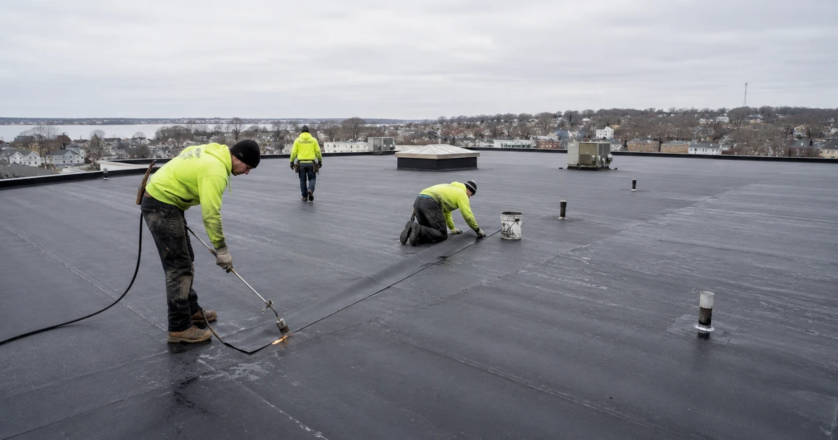 Commercial roofing crew installing membrane on a Worcester MA flat roof